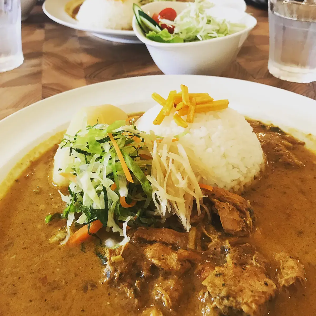 平尾台高原スパイシーカレーセット。カレーライスに千切り野菜がのり、サラダが添えられている