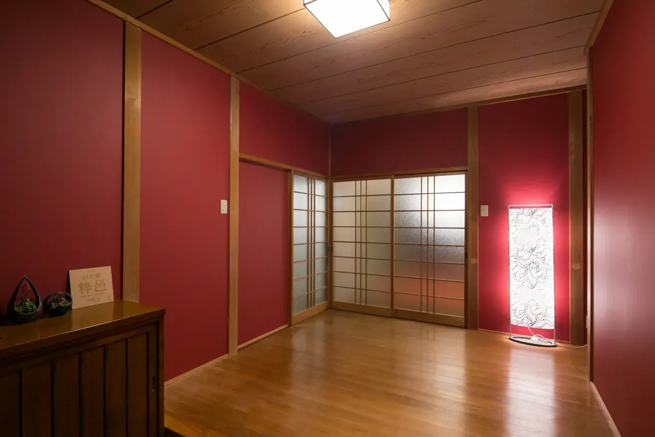板の間。赤い壁と障子、板張りの床の広い部屋